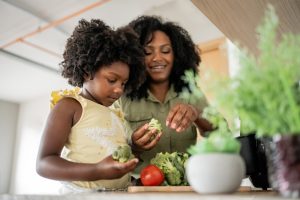 Mother teaching daughter how to prepare vegetables in an oil-free fryer